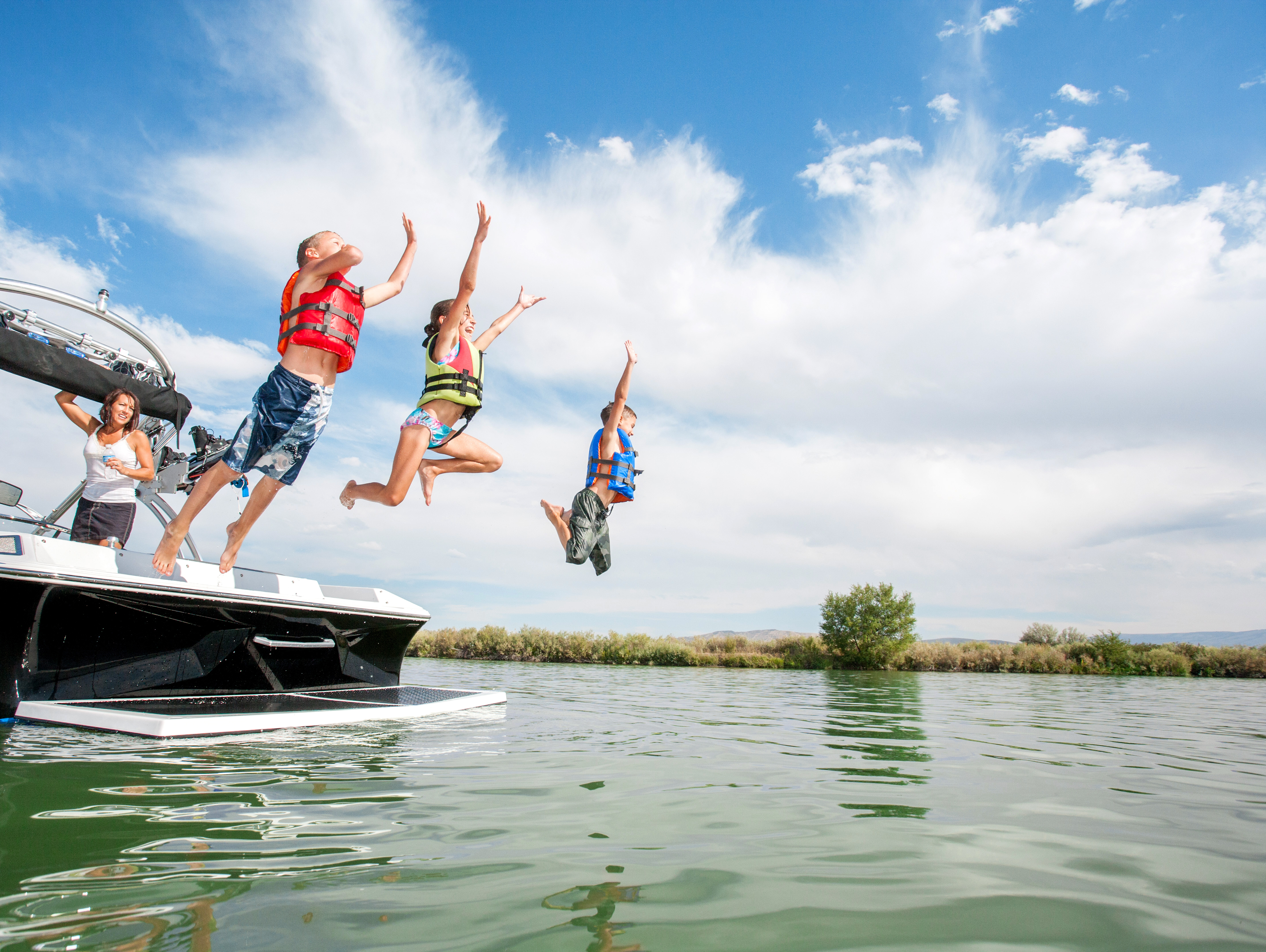 People wearing life jackets while jumping into the water. 