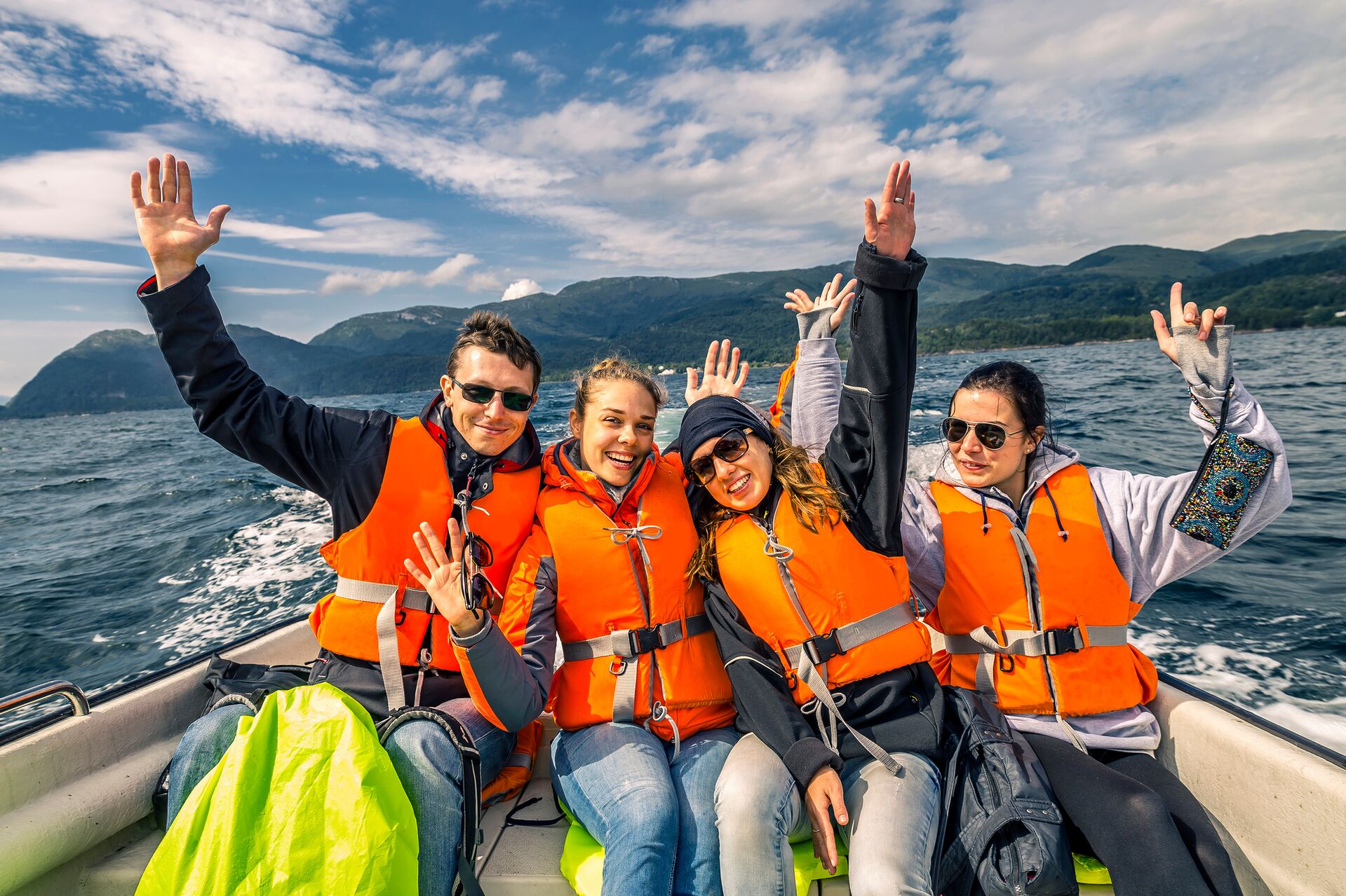 People wearing orange life jackets at the back of a boat, benefits of using a boat loan calculator concept. 