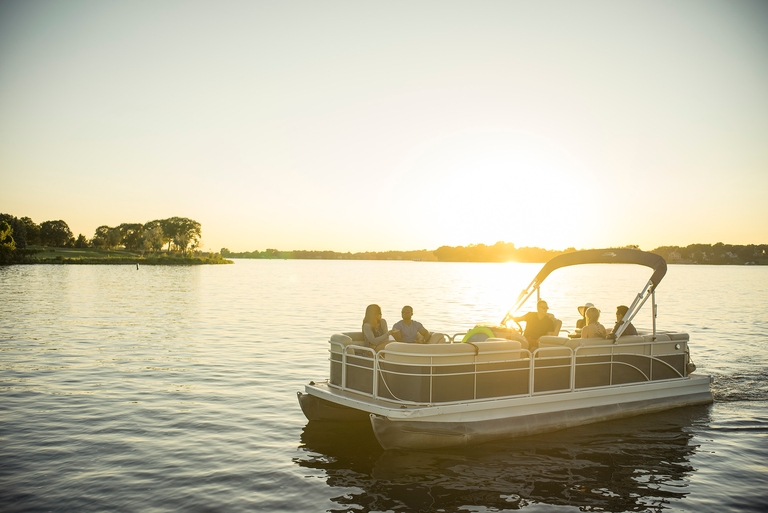 A pontoon boat on the water at dusk. 