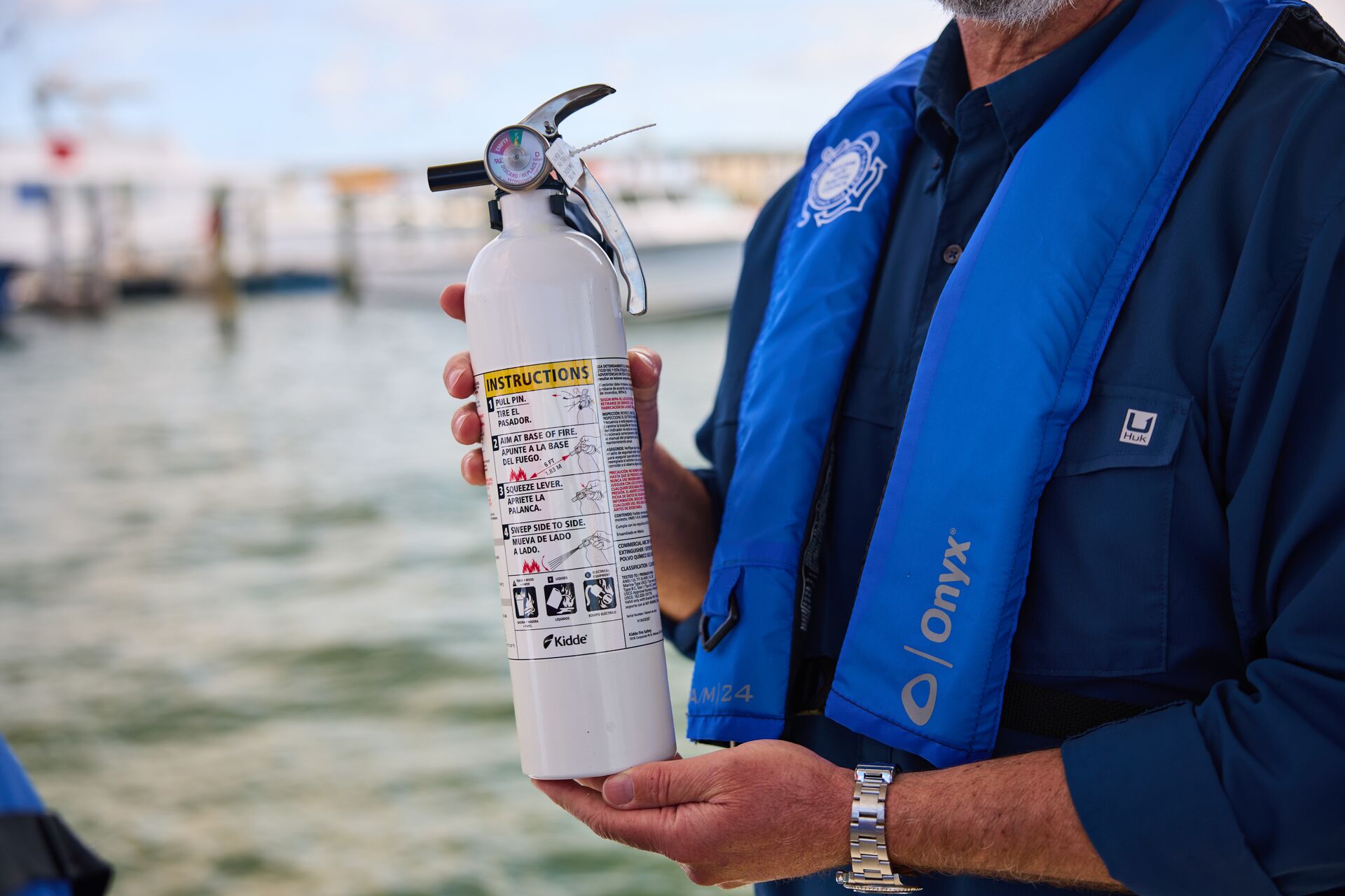 Close-up of a boater in a lifejacket holding a fire extinguisher, safety equipment concept. 