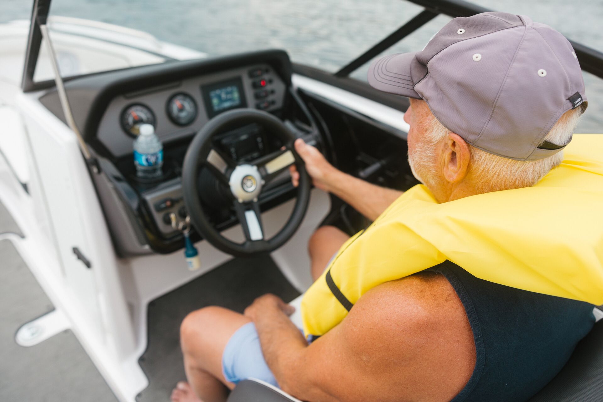 A man wearing a yellow lifejacket drives a boat, renting boats concept. 